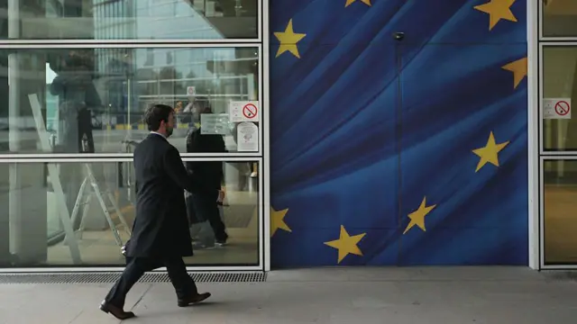 Un hombre atraviesa una puerta que lleva pintada la bandera de la Unión Europea.