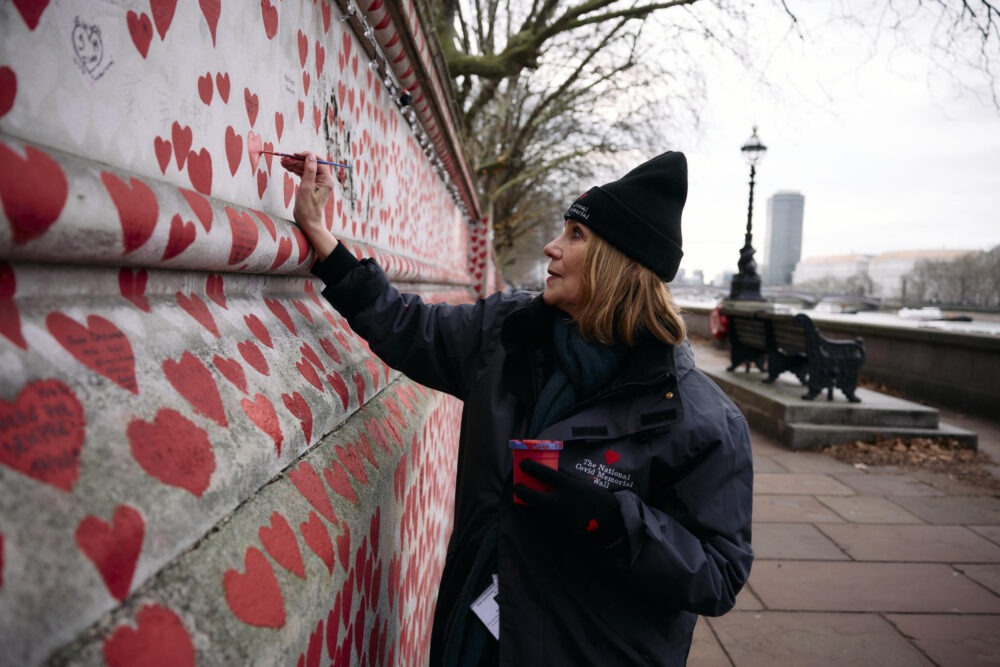 La voluntaria Lorelei King pinta un corazón en el Muro Nacional del Covid de Londres, dedicado a los fallecidos por el covid-19, el 20 de diciembre de 2024