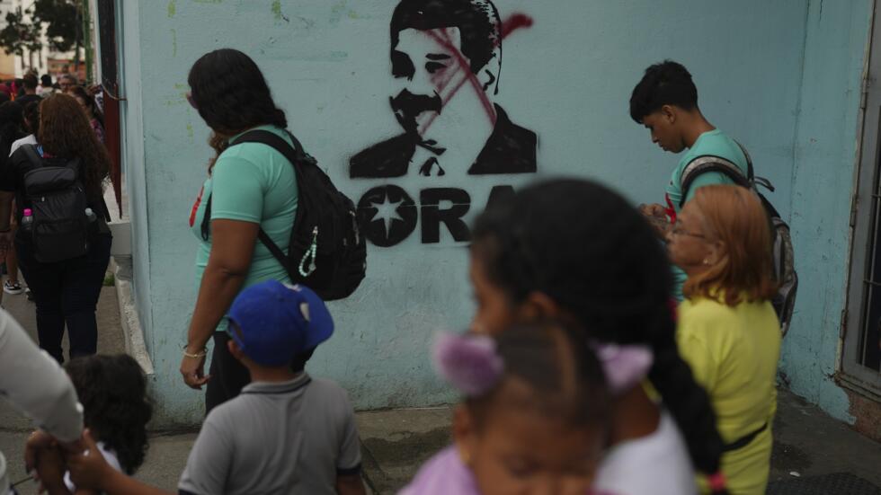 La gente camina junto a un mural del presidente Nicolás Maduro con una X dibujada sobre su rostro en Caracas, Venezuela, el lunes 6 de enero de 2025.