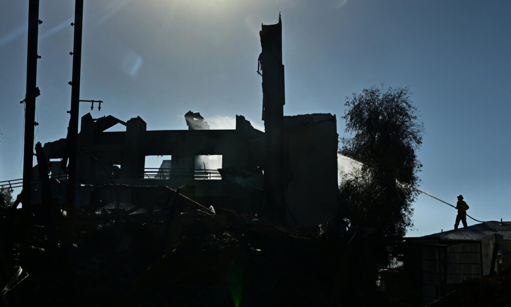 Un bombero rocía una estructura quemada por el incendio de Palisades en el lujoso barrio de Pacific Palisades de Los Ángeles