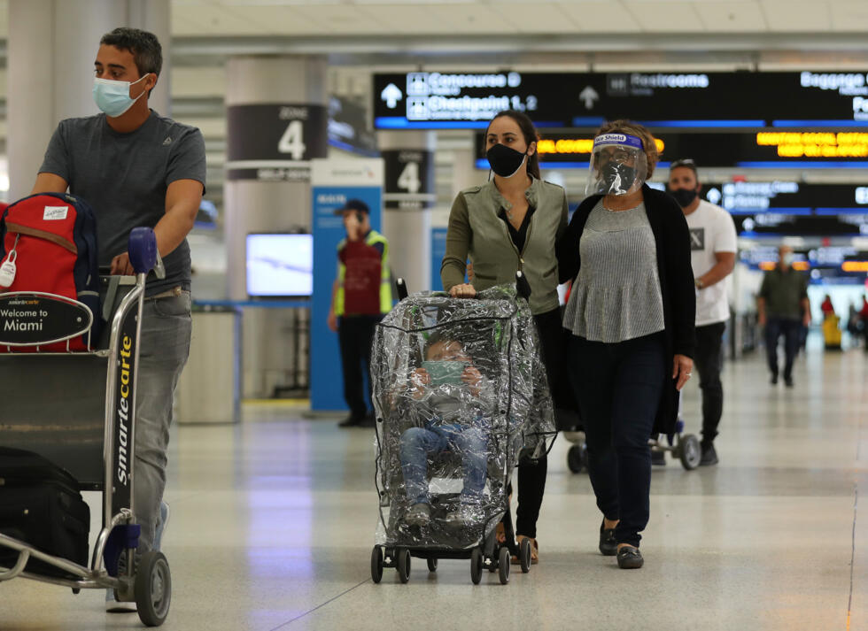 Viajeros con mascarillas e incluso una visera protectora caminan por el aeropuerto internacional de Miami, el 1 de febrero de 2021 en esa ciudad de EEUU