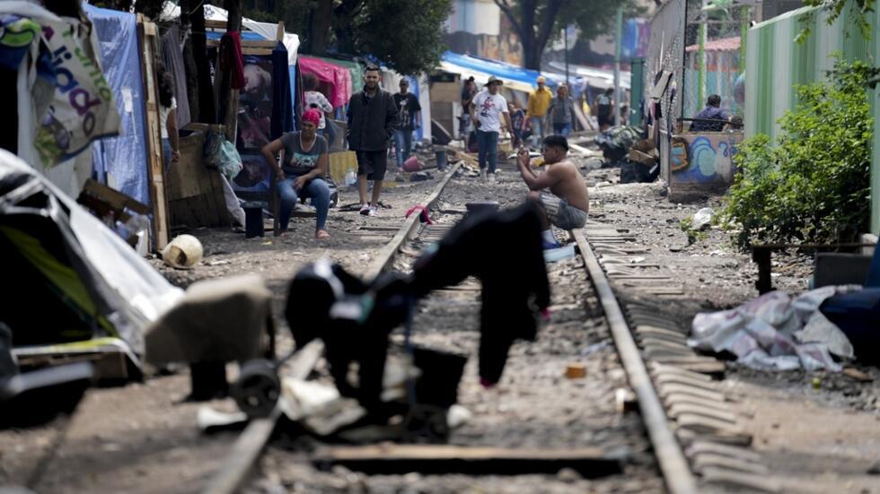 Migrantes esperan ayuda tras las fuertes lluvias en un campamento de tiendas de campaña instalado a lo largo de la línea ferroviaria de Vallejo, en Ciudad de México, el 18 de julio de 2024.