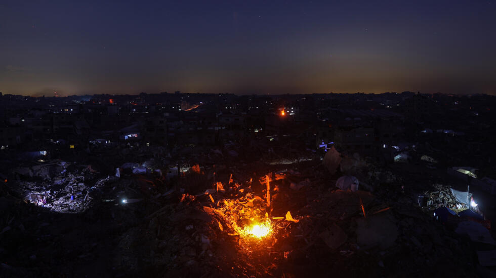 Una fogata encendida entre edificios destruidos en Jabaliya, en el norte de la Franja de Gaza, el 18 de febrero de 2025