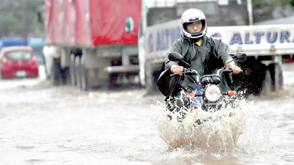 Un motociclista sortea el agua producto de las intensas lluvias en la capital cruceña./ APG