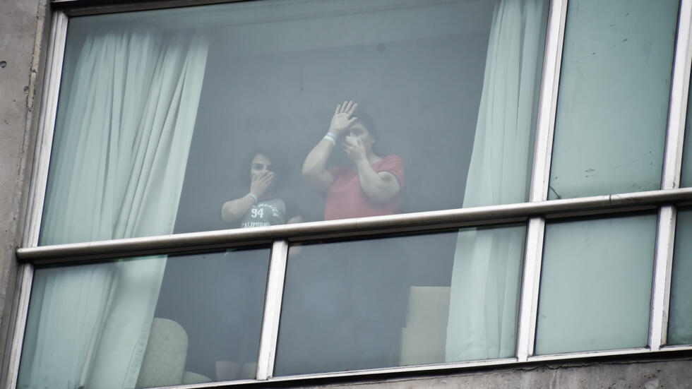 Migrantes deportados de Estados Unidos intentan comunicarse desde la ventana de la habitación del hotel en el que están retenidos en Ciudad de Panamá, 19 de febrero de 2025.