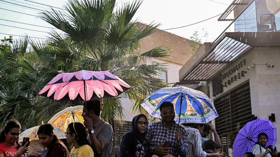 Unos turistas con sombrillas visitan la Calle de la Lluvia en Sharjah, en Emiratos Árabes Unidos, el 14 de julio de 2024