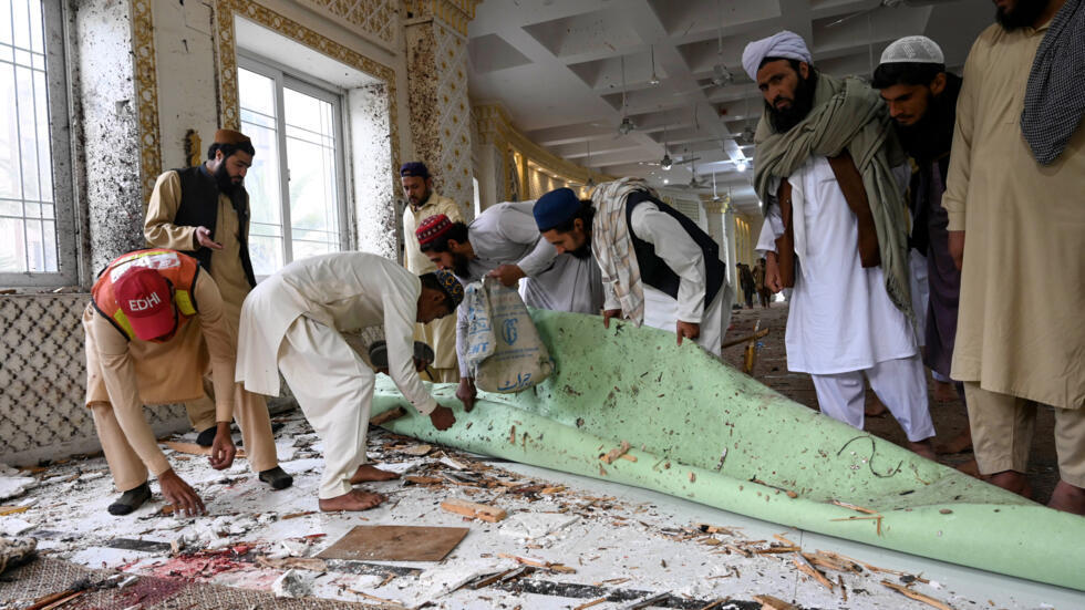 Varios hombres retiran escombros tras un ataque suicida ocurrido durante la oración del viernes en la escuela coránica de Akora Khattak, al este de Peshawar, el 28 de febrero de 2025 en Pakistán