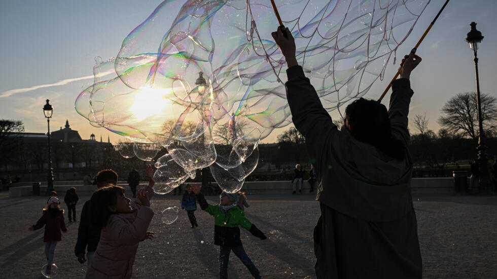 Una mujer genera pompas de jabón gigantes para que unos niños jueguen, el 4 de marzo de 2025 al atardecer en los Jardines de las Tullerías, en París