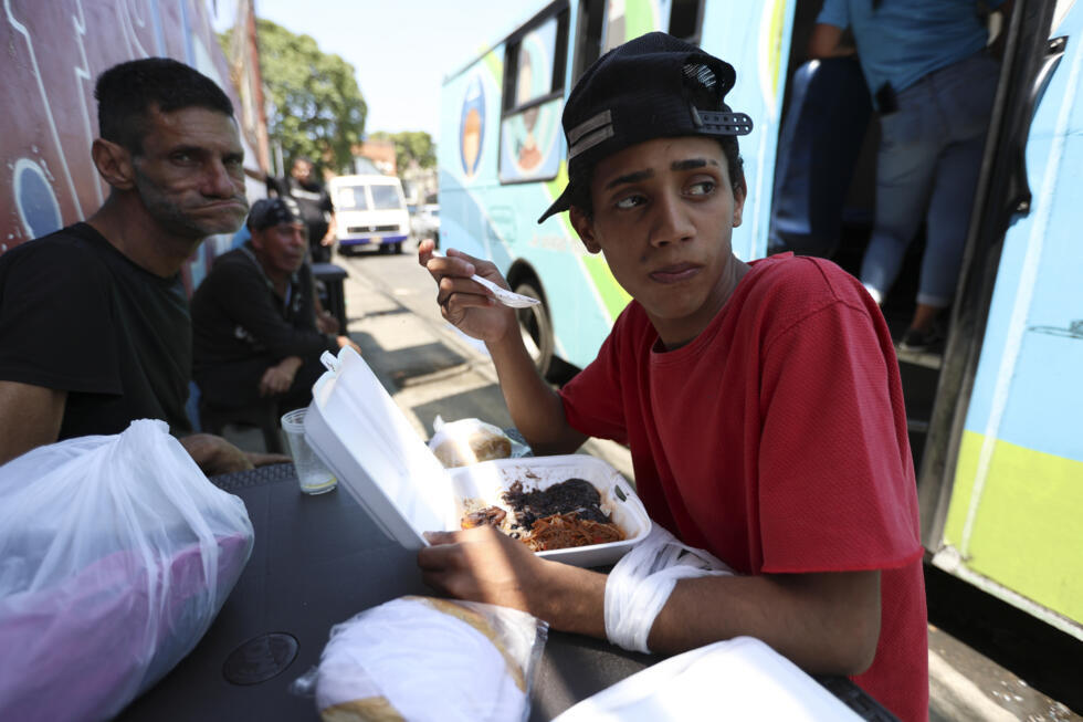 Un grupo de personas sin hogar recibe una comida de la Fundación Panabus, beneficiaria del banco de alimentos de Venezuela, el 26 de febrero de 2025 en Caracas.