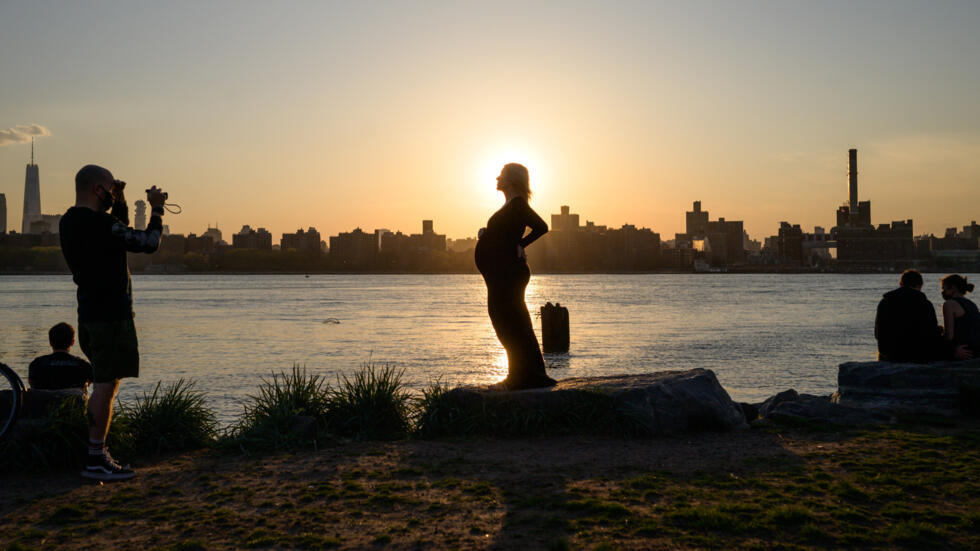 Una mujer embarazada posa durante una sesión de fotos en un parque en Williamsburg, en Nueva York, con Manhattan de fondo, el 20 de abril de 2021