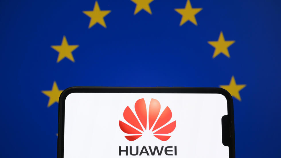 El logotipo de la empresa de telecomunicaciones china Huawei en un teléfono móvil, delante de una bandera de la Unión Europea, fotografiado en Bruselas el 13 de marzo de 2025