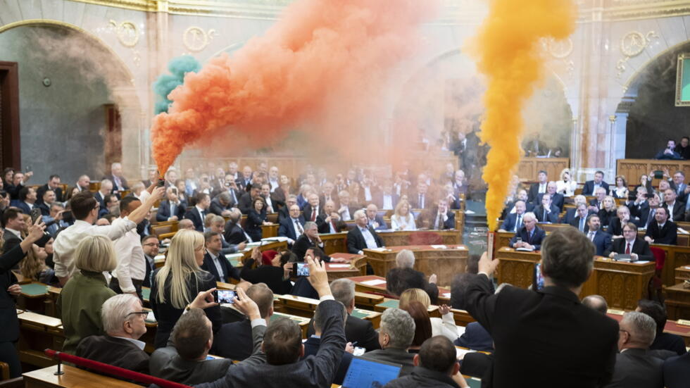 Diputados de Momentum protestan con bengalas durante la sesión plenaria del Parlamento húngaro en Budapest, el 18 de marzo de 2025.