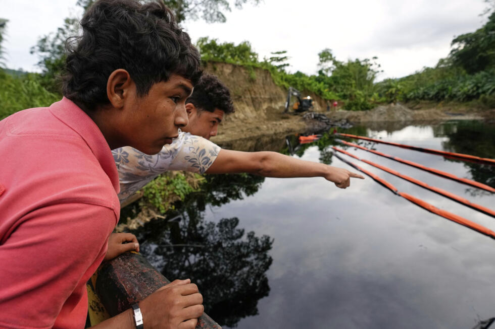 Habitantes observan a los trabajadores de la compañía petrolera estatal limpiando un derrame de petróleo causado por un deslizamiento de tierra que rompió un oleoducto a lo largo del río Viche en Cube, Ecuador. Marzo de 2025.