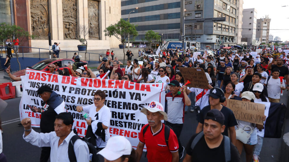 Manifestantes marchan en Lima con pancartas contra la violencia durante una movilización nacional contra el crimen organizado y el sicariato, convocada por organizaciones sociales y políticas el 21 de marzo de 2025.