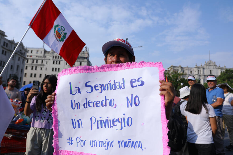 Un manifestante sostiene una pancarta durante una marcha contra el crimen organizado y el sicariato en Lima, el 21 de marzo de 2025.