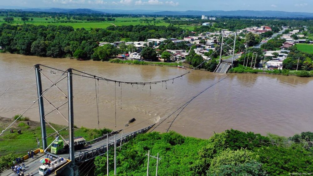 Imagen del puente totalmente hundido con dos camiones de gran tonelaje en uno de sus extremos.