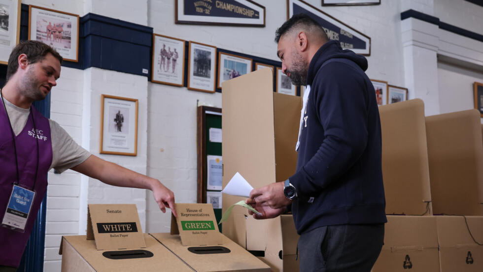 Un funcionario ayuda a un votante a insertar su boleta en las elecciones generales de Australia, el 3 de mayo de 2025 en Sídney