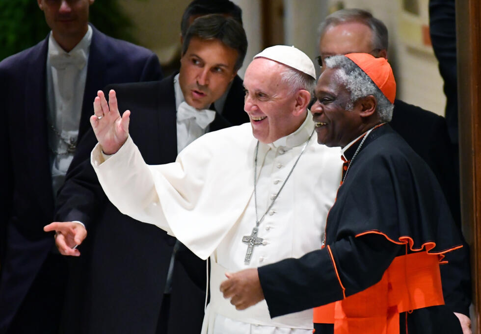 El papa Francisco (c), flanqueado por el cardenal Peter Turkson (drcha.), saluda durante el Encuentro Mundial de Movimientos Populares, en Ciudad del Vaticano, el 5 de noviembre de 2016