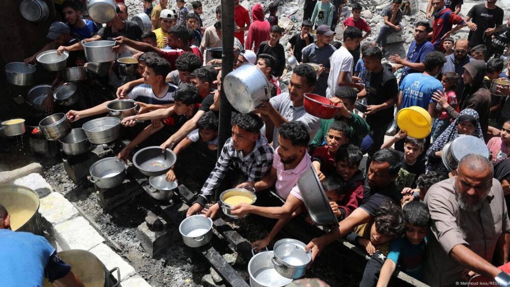 Personas con recipientes, a la espera de recibir alimentros en Gaza.
