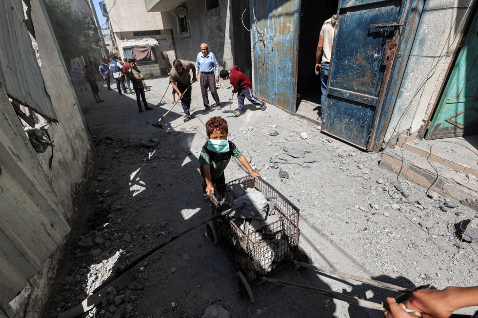 Un hombre y un niño transportan un carro cargado de escombros tras bombardeos israelíes en el campo de refugiados de Bureij, en el centro de la Franja de Gaza, el 23 de mayo de 2025