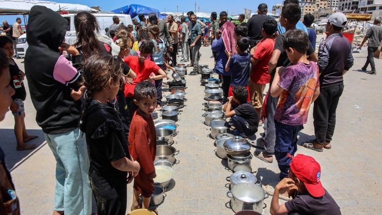 Palestinos hacen fila para recibir una comida caliente en un punto de distribución en la ciudad de Gaza