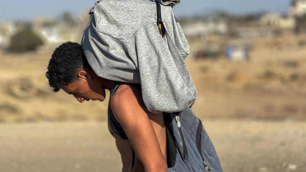 Un palestino carga con ayuda tras una distribución de GHF en Rafah, en el sur de la Franja de Gaza, el 27 de mayo de 2025