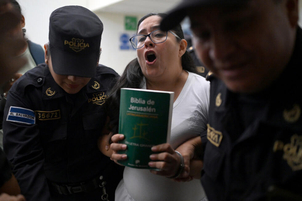 La abogada y activista de derechos humanos salvadoreña Ruth López, con una biblia en las manos, es escoltada por la policía a una audiencia en el centro judicial Isidro Menéndez de San Salvador, el 4 de junio de 2025