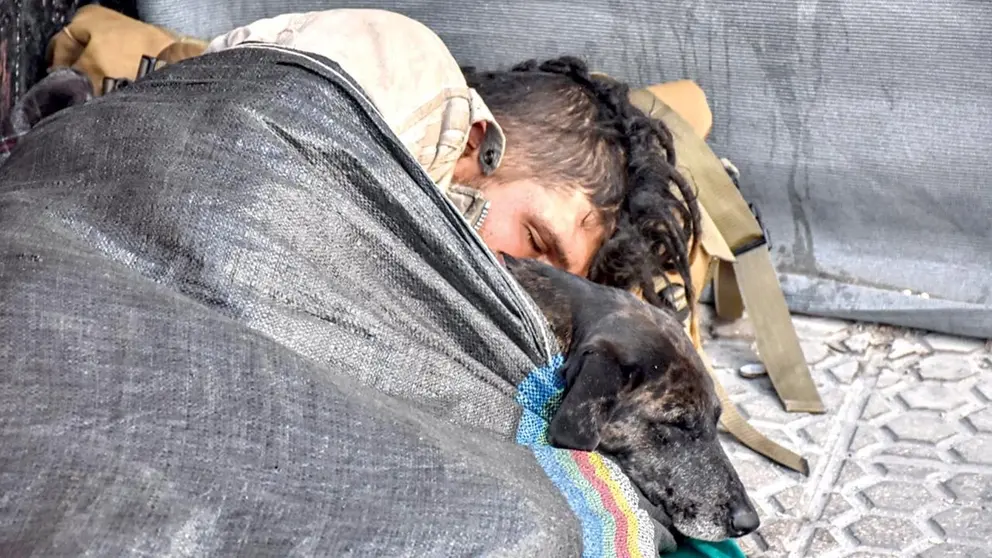 Una persona en situación de calle se cobija de frío con su mascota./ DICO SOLÍS