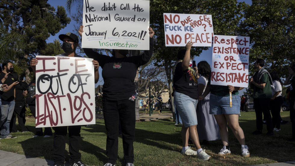 Unos manifestantes muestran unos carteles tras el arresto de un hombre que viajaba en un vehículo con su familia por parte de unos agentes federales, el 11 de junio de 2025 en Boyle Heights, al este de Los Ángeles
