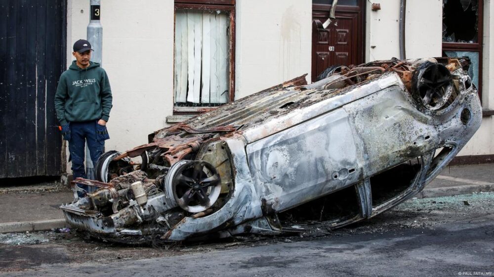 Un hombre junto a un vehículo quemado en Ballymena, Irlanda del Norte.