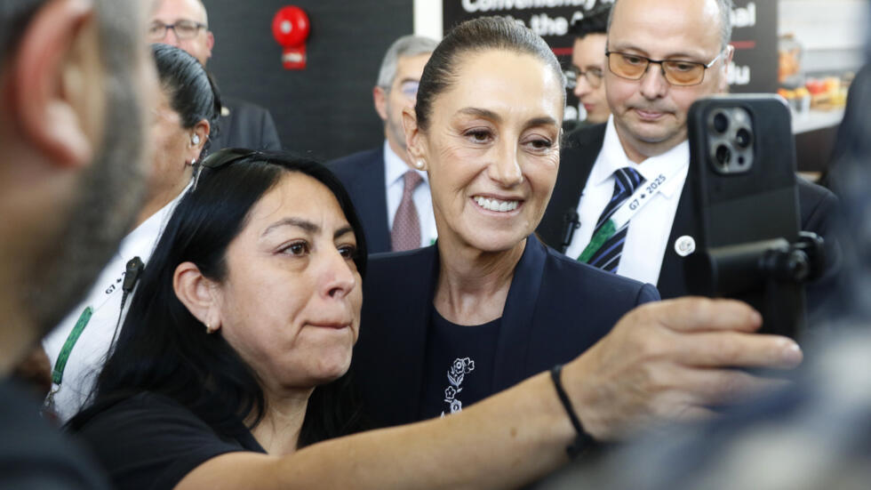 La presidenta de México, Claudia Sheinbaum (drcha.), se fotografía con una mujer a su llegada al aeropuerto internacional de Calgary, en Canadá, el 16 de junio de 2025, para asistir a la cumbre del G7