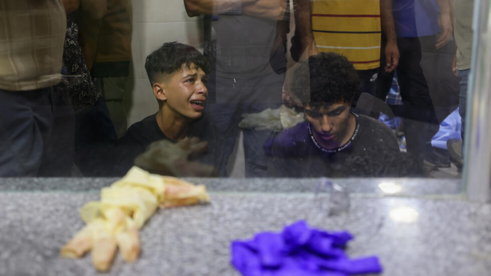En el hospital Al Awda del campo de desplazados de Nuseirat, en el centro de la Franja de Gaza, jóvenes palestinos lloran la muerte de un allegado tras un ataque israelí en un punto de entrega de alimentos instalado por EEUU, el 24 de junio 2025