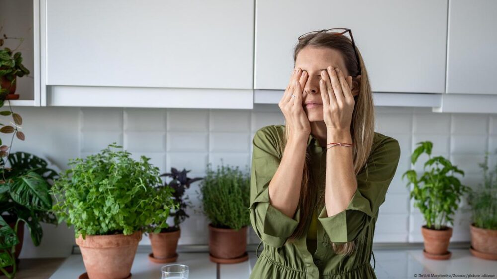 Mujer somnolienta que sufre de insomnio se frota los ojos en la cocina de su casa a primera hora de la mañana.