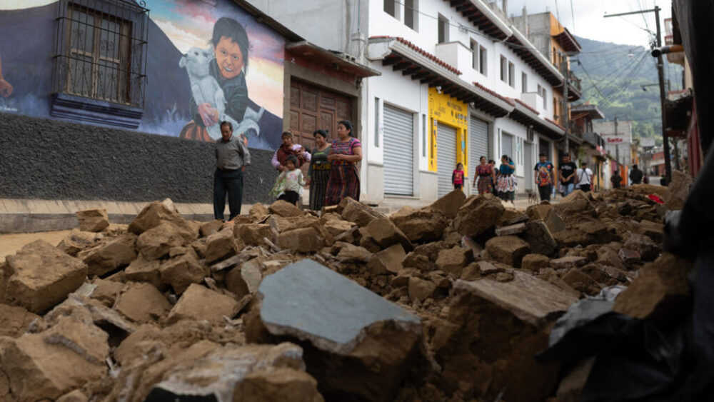 La gente camina frente a la pared derrumbada de una casa durante una serie de terremotos en Santa María de Jesús, Guatemala, el 9 de julio de 2025