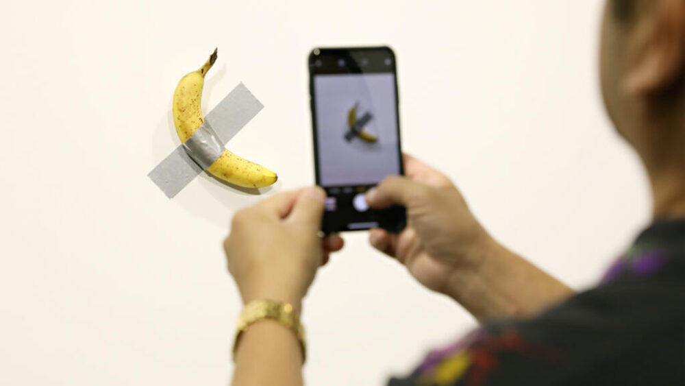 Un visitante toma una foto de la obra "Comedians", del artista Maurizio Cattelan, en la galería Perrotin durante el evento Art Basel Miami, el 6 de diciembre de 2019 en Miami