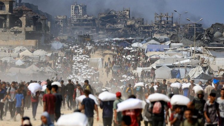 Palestinos se reúnen para recibir ayuda humanitaria en medio de una crisis de hambre, en Beit Lahia.