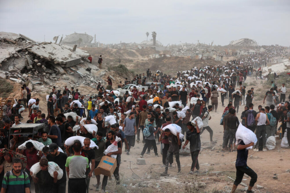 Palestinos cargan con paquetes de ayuda humanitaria distribuidos en Beit Lahia, en el centro de la Franja de Gaza, el 29 de julio de 2025