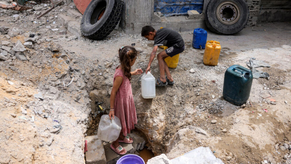 Una niña y un niño llenan garrafas de agua con la aún sobrante en una tubería subterránea, el 24 de abril de 2025 en Beit Lahia, al norte de la Franja de Gaza
