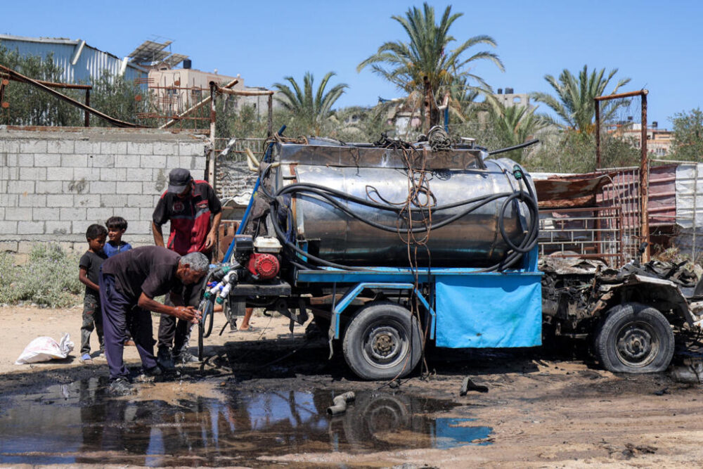 Un hombre se lava con el agua de una camioneta cisterna alcanzada por un bombardeo israelí contra el campo de refugiados palestinos de Nuseirat, el 14 de julio de 2025 en el centro de la Franja de Gaza