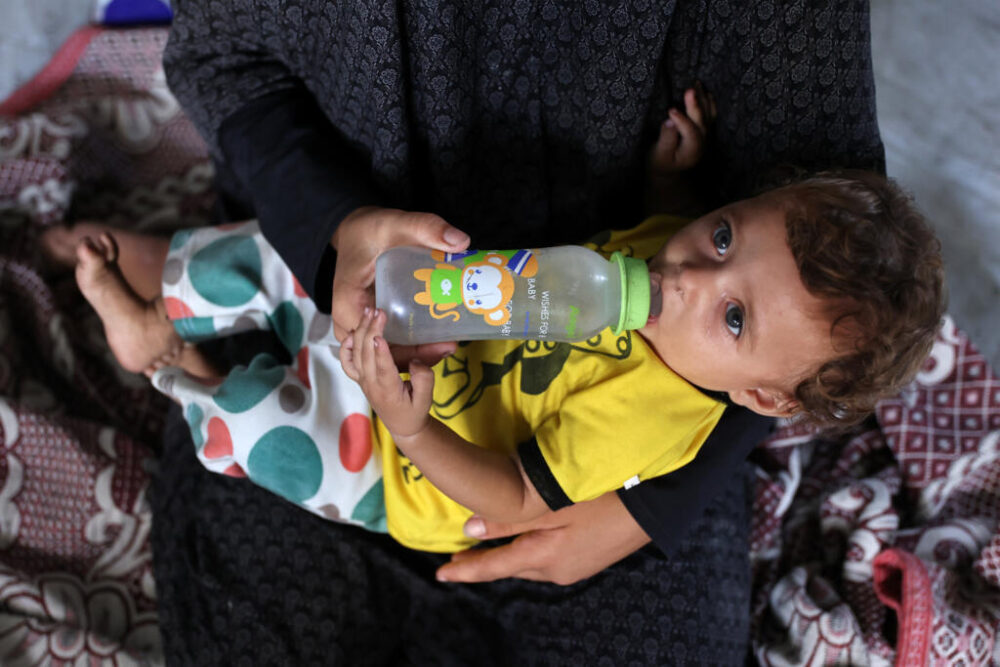 La niña palestina de siete meses de edad Janin Sobh bebe agua de un biberón en una tienda de campaña del barrio de Daraj, el 3 de agosto de 2025 en la ciudad de Gaza