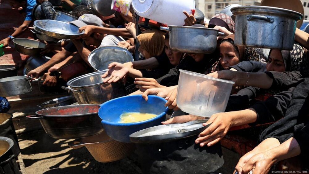 Una multitud de personas pide alimentos con recipientes en las manos en Gaza.