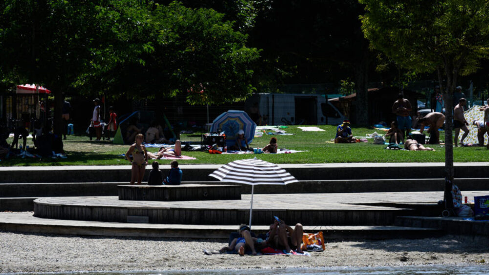 Personas descansan bajo una sombrilla en la playa del lago de Le Bourget en Le Bourget-du-Lac, en el centro este de Francia, el 8 de agosto de 2025.