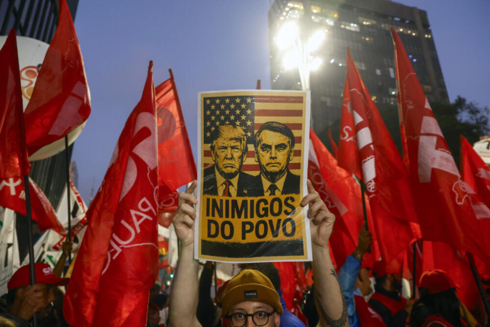 Un hombre sostiene un cartel con las imágenes de Donald Trump (izq) y Jair Bolsonaro sobre la frase 'Enemigos del pueblo', durante una manifestación celebrada el 10 de julio de 2025 en la ciudad brasileña de Sao Paulo