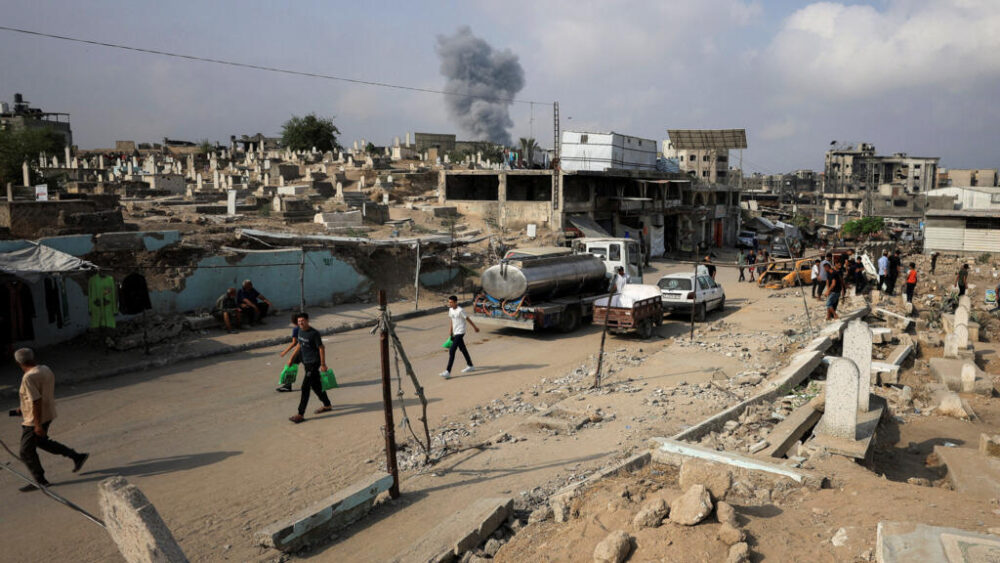 Palestinos en la ciudad de Gaza, mientras se eleva el humo tras un ataque israelí, el 13 de agosto de 2025.