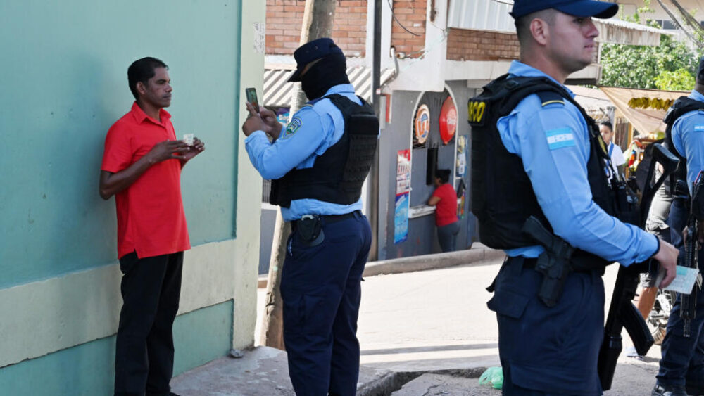 Un hombre es fotografiado por un policía durante un patrullaje en calles de Tegucigalpa, el 14 de agosto de 2025, en medio de un estado de excepción vigente desde 2022 que, según la ONG Cristosal, ha propiciado casos de torturas y abusos de poder.