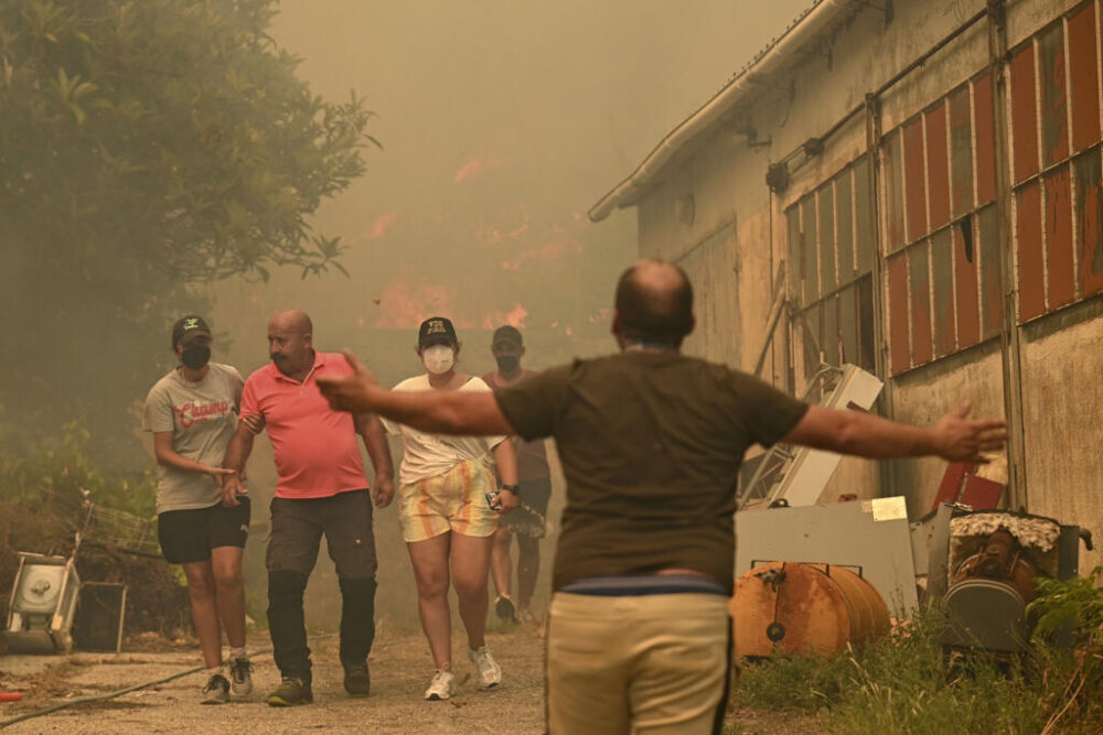 Varias personas evacuan una zona afectada por un incendio forestal en Vilarino, en el municipio español de Carballeda de Avia, ubicado en la provincia noroccidental de Ourense, el 17 de agosto de 2025