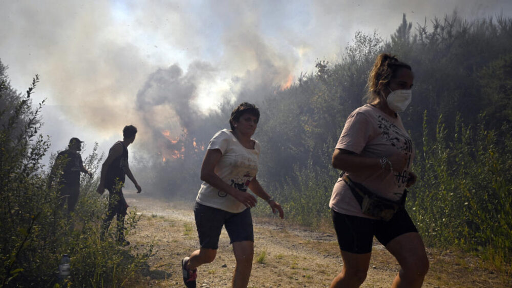 Personas huyendo del fuego cerca del pueblo de Melón, en el noroeste de España, el 17 de agosto de 2025. Los bomberos siguen luchando contra los incendios en el noroeste y el oeste del país, con unidades del ejército desplegadas para ayudar a contener las llamas. Francia e Italia habían enviado anteriormente aviones cisterna a una base aérea cerca de Salamanca para ayudar en las labores de extinción.