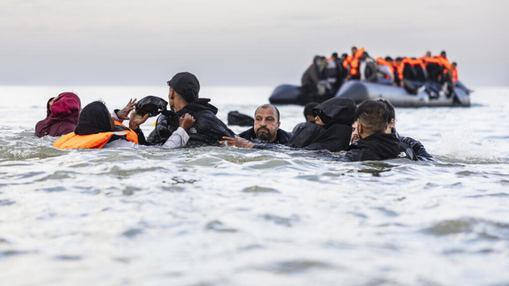 Unos migrantes se quedan sin alcanzar una embarcación de traficantes de personas para cruzar el canal de La Mancha el 12 de agosto de 2025 en una playa de Gravelines, en el norte de Francia