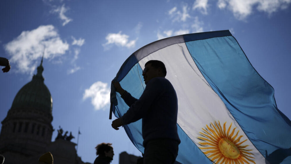 Un manifestante sostiene una bandera nacional frente al Congreso mientras los legisladores debaten el veto del presidente Javier Milei a un proyecto de ley para ampliar las protecciones a las personas con discapacidad en Buenos Aires, Argentina, el miércoles 20 de agosto de 2025.