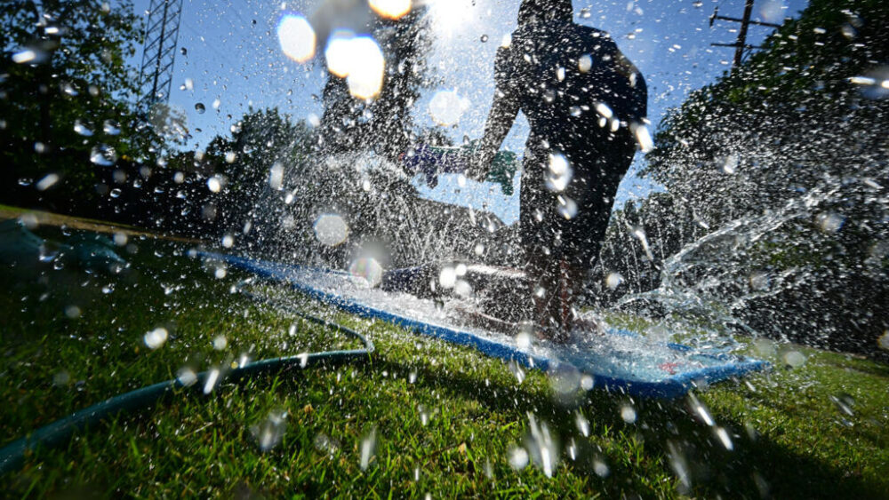 Un niño se refresca con un aspersor en Fresno, California (EEUU), el 17 de junio de 2022, durante un prolongado periodo de efectos del fenómeno climático La Niña